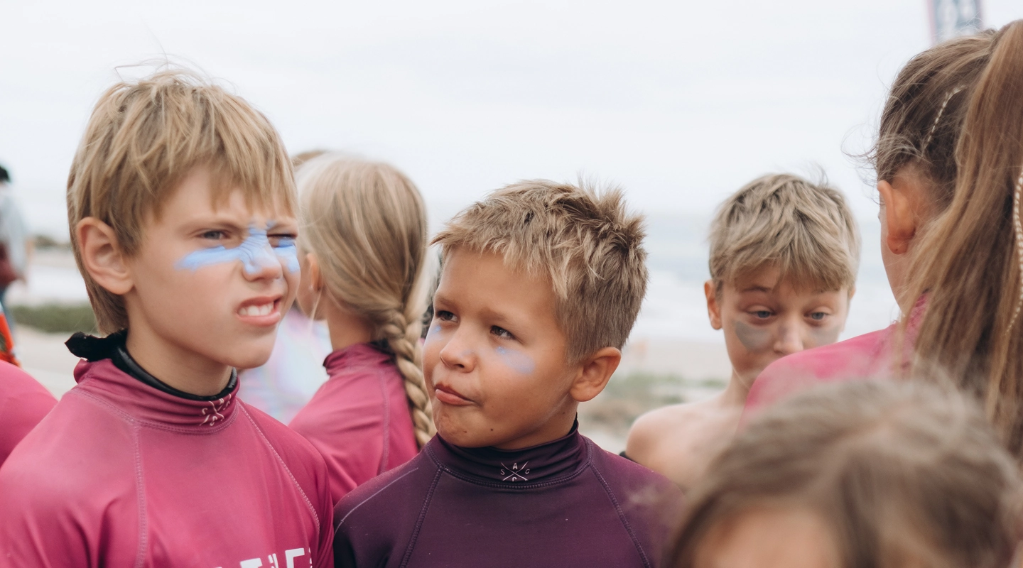 Group of children in maroon Native Açaí shirts with blue face paint standing outdoors.